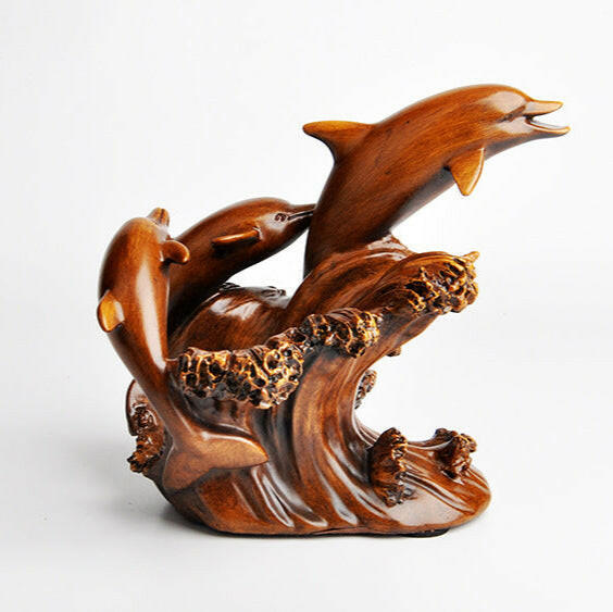 Wooden sculpture of dolphins leaping out of water on a white background