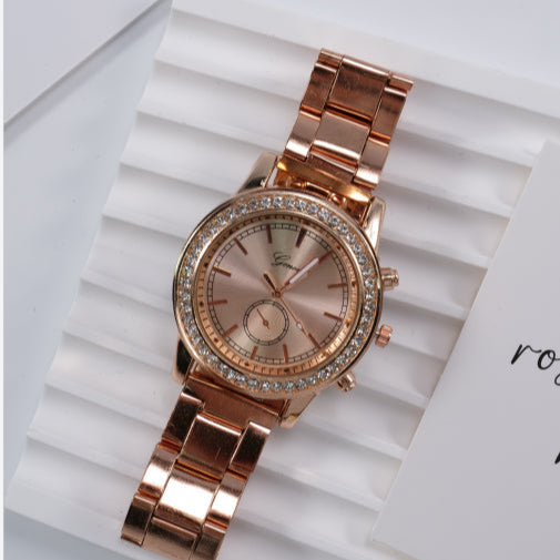 Rose gold watch with diamond accents on a white textured surface