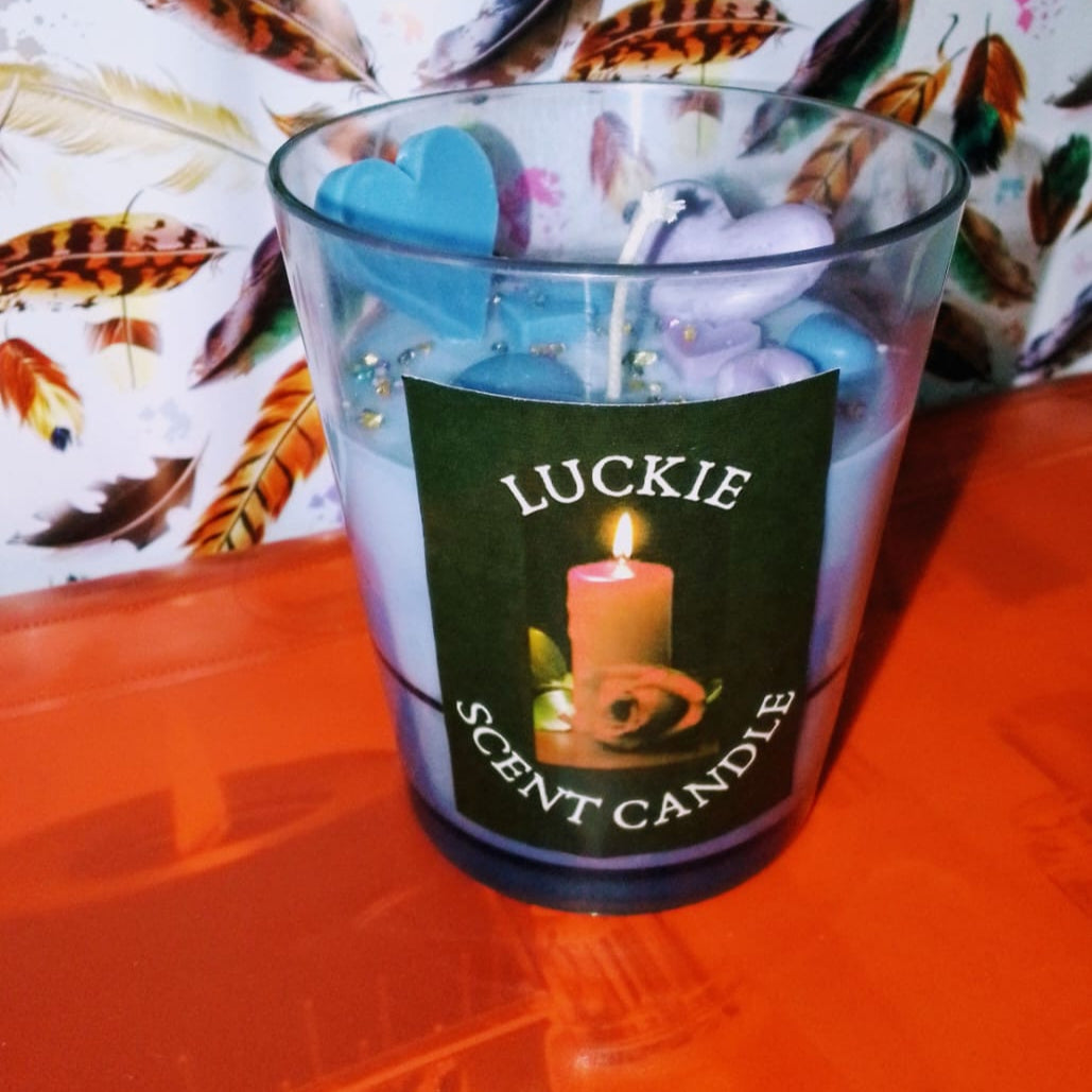 Candle in a glass container with a 'Luckie Scent Candle' label on a colorful background.