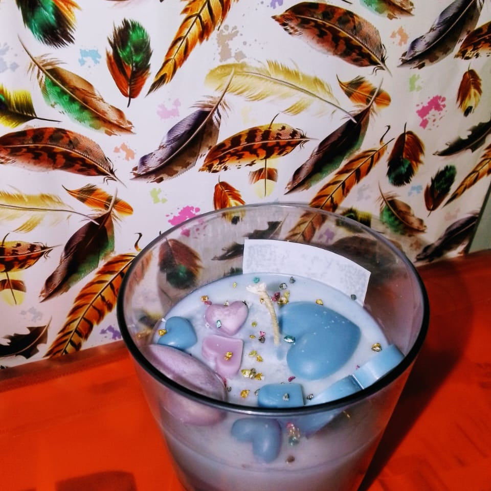 Glass of colorful drink with a card on a table with feather-patterned paper in the background