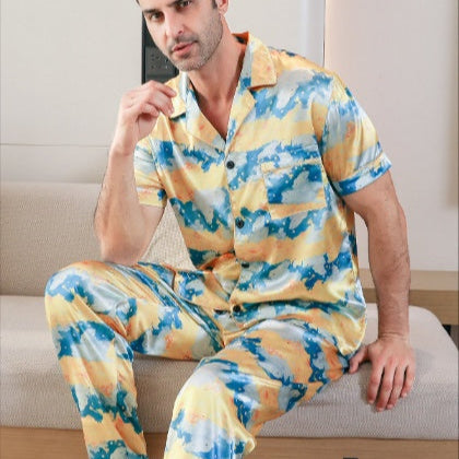 Man wearing a colorful pajama set sitting on a couch.