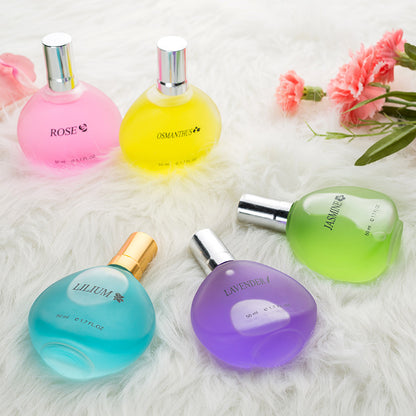 Five colorful perfume bottles with floral names on a white textured surface.
