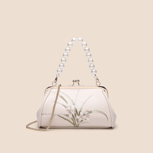 White handbag with floral design and pearl handle on beige background
