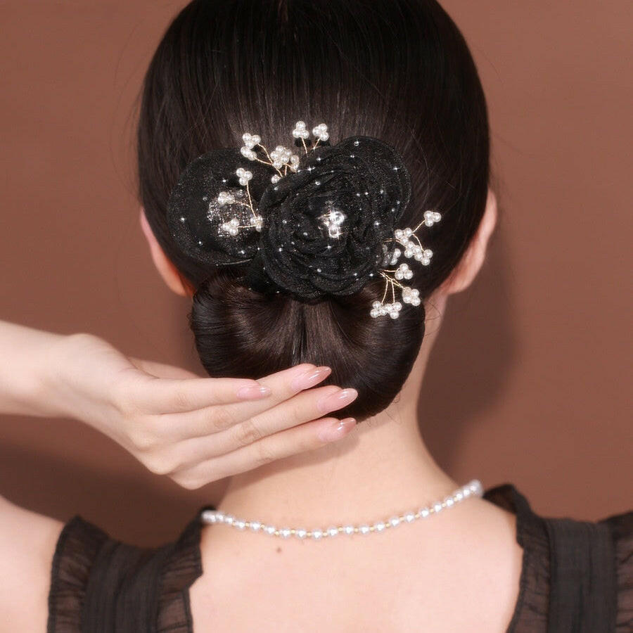Woman with a decorative hairpiece and pearl necklace against a brown background