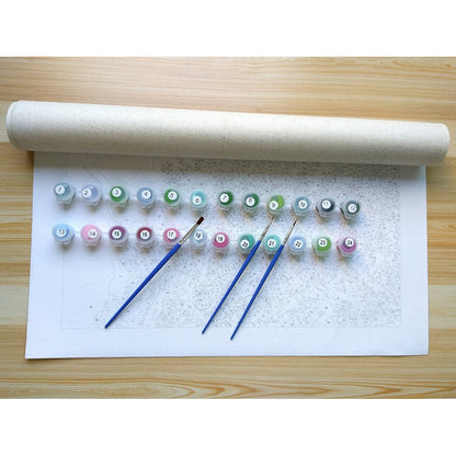 Set of small bottles with colorful labels and paintbrushes on a white paper roll against a wooden surface.