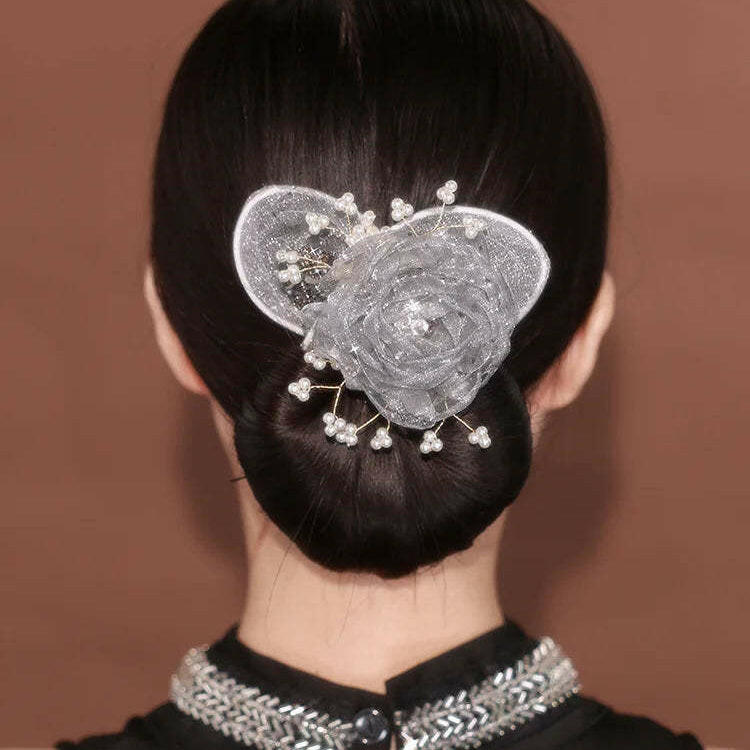 Person with elegant hair bun adorned with decorative hairpiece against a brown background