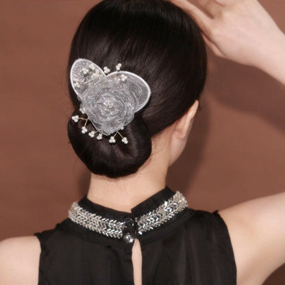 Woman with a decorative hairpin in her bun against a brown background