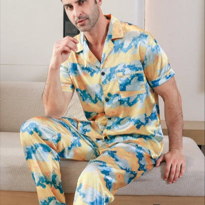 Man wearing a colorful pajama set sitting on a couch.