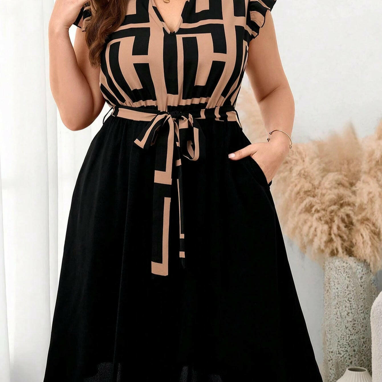 Woman wearing a black and beige patterned dress with a white background